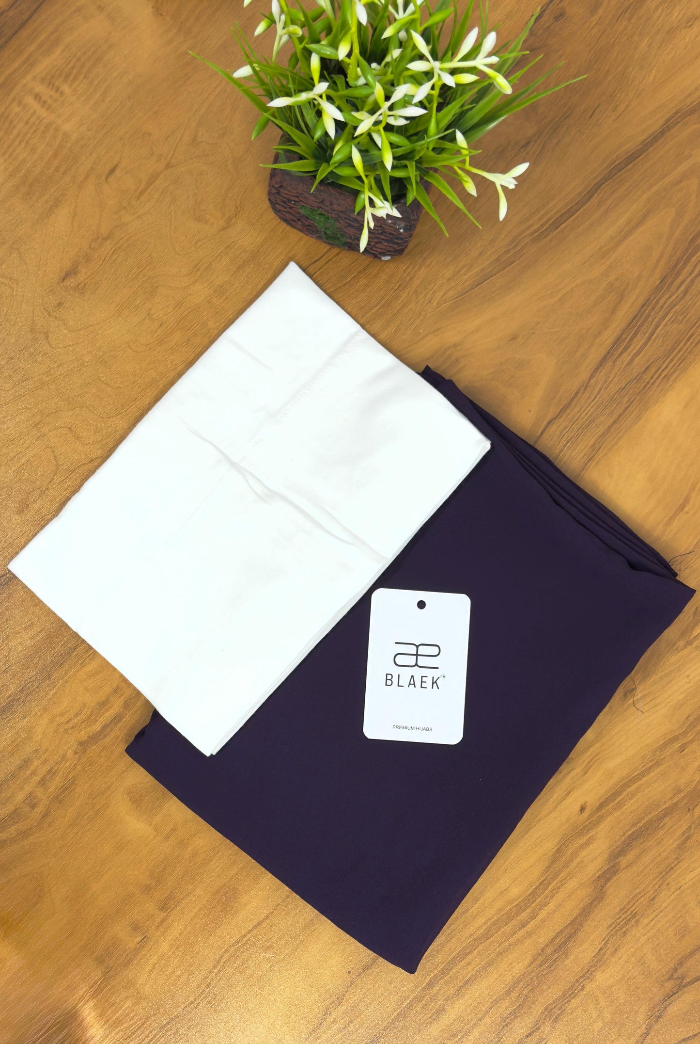 Eggplant slider hijab paired with white cap, folded.